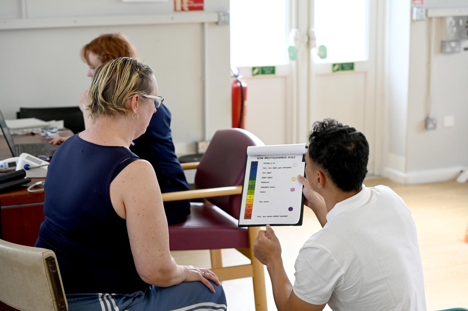 Patient with clinician checking results on clipboard in gym